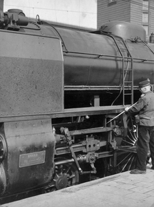 222814 Afbeelding van een machinist tijdens het smeren van het drijfwerk van een (Zweedse) stoomlocomotief uit de serie ...